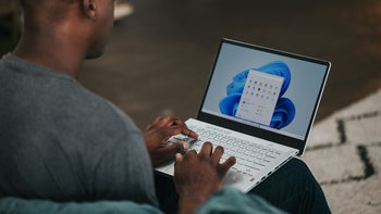 A person sitting with a Windows 11 laptop.