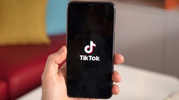A smartphone held in a hand showing the TikTok logo on the display.