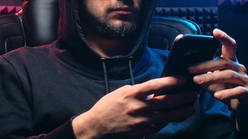 Scammer looks at his phone as he seeks to steal personal data from a victim.